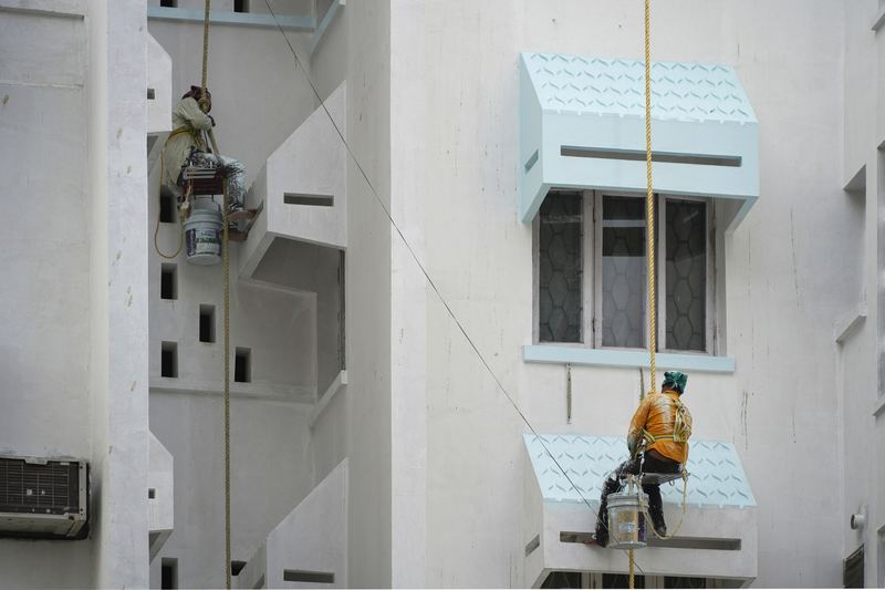 Wall painters working on ropes on a facade